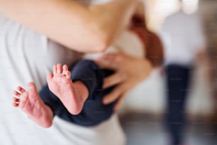 Eine Mutter, die ein Neugeborenes zu Hause hält, Nahaufnahme von nackten Füßen im Vordergrund.