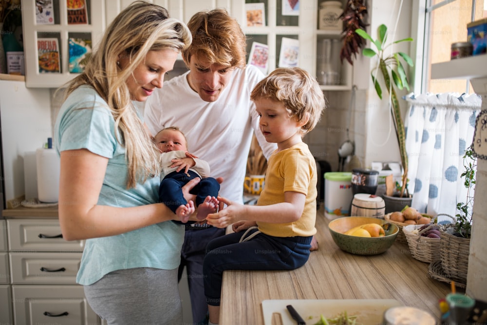 Young parents with a newborn baby and small toddler son at home.