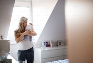 A beautiful young mother holding a newborn baby at home. Copy space.