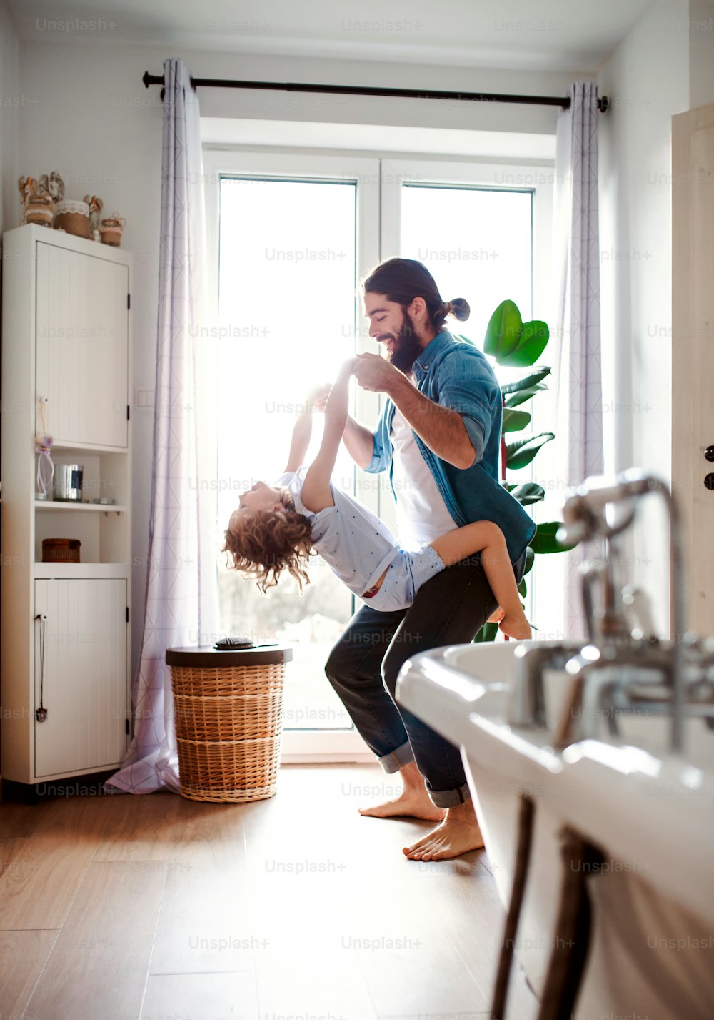 Uma menina pequena com pai jovem no banheiro em casa, se divertindo.