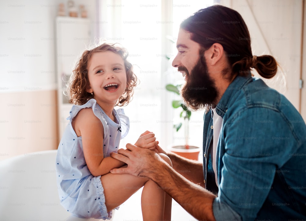 Une petite fille mignonne avec un jeune père à la maison, en train de parler. Espace de copie.