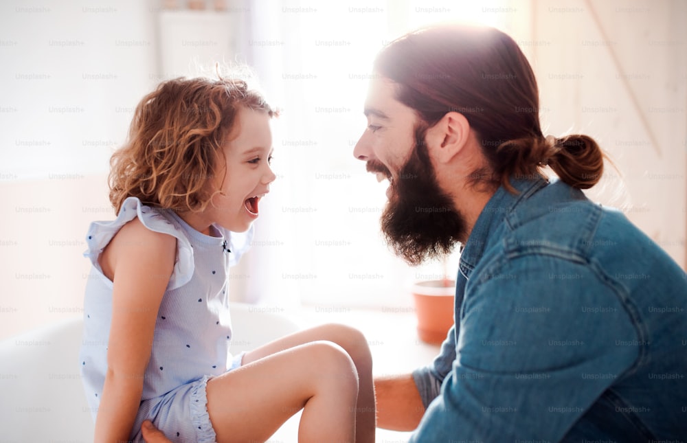 A cute small girl with young father at home, talking.