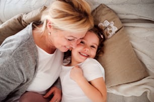 A top view portrait of small girl with grandmother having fun at home. Copy space.