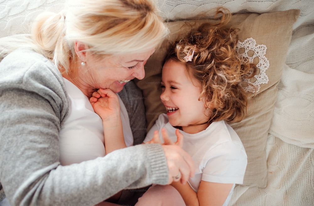 A top view portrait of small girl with grandmother having fun at home. Copy space.