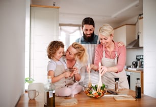 Un retrato de una niña pequeña con sus padres y abuela en casa, preparando ensalada de verduras.