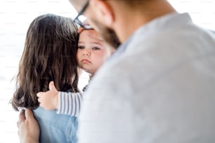 Uma jovem família com uma criança chorando infeliz em pé dentro de casa em casa.