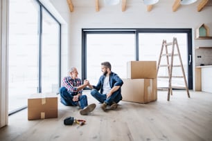 A portrait of mature man with his senior father shaking hands when furnishing new house, a new home concept. Copy space.