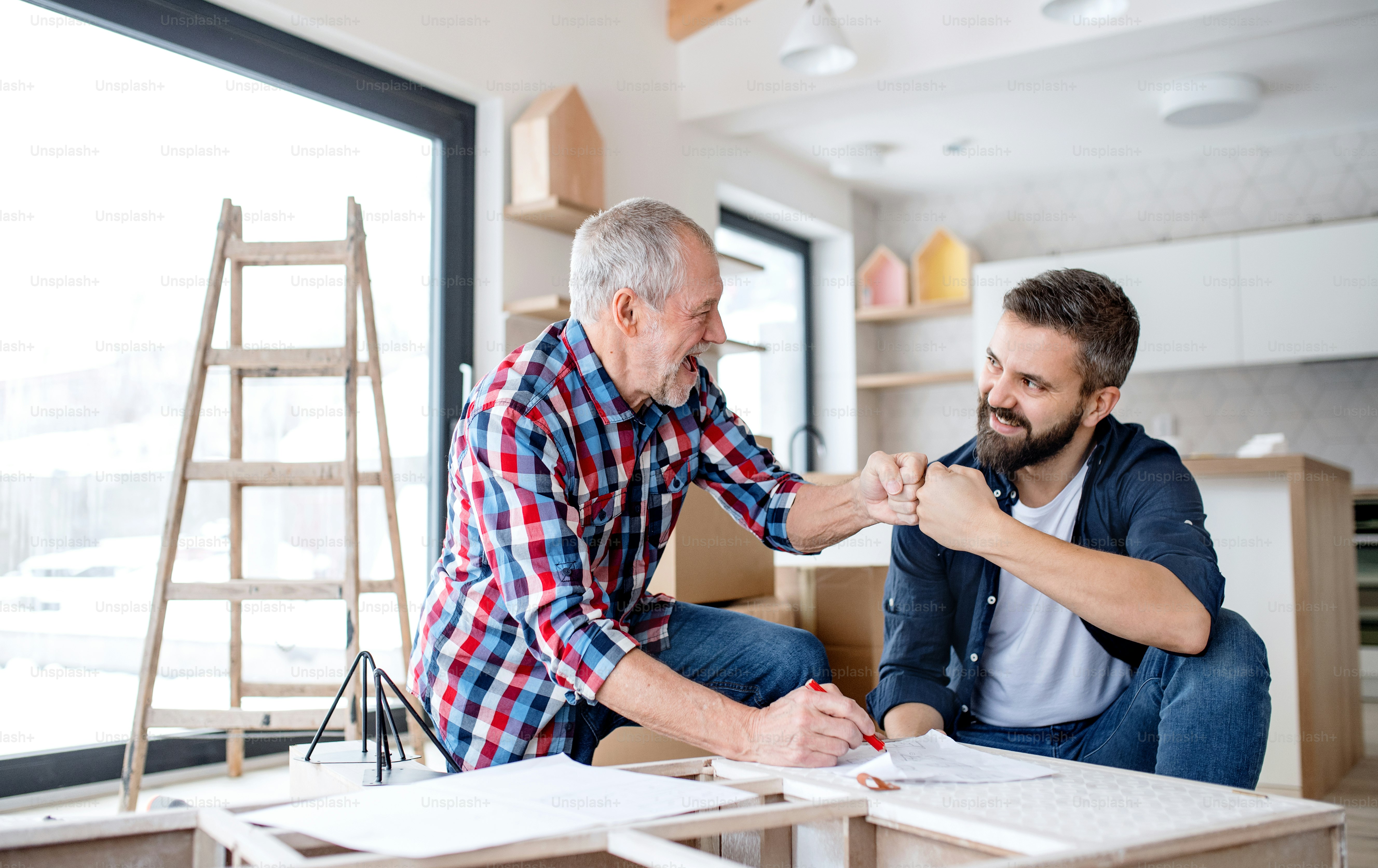 Un uomo maturo hipster con il padre anziano che assembla mobili, un nuovo concetto di casa.
