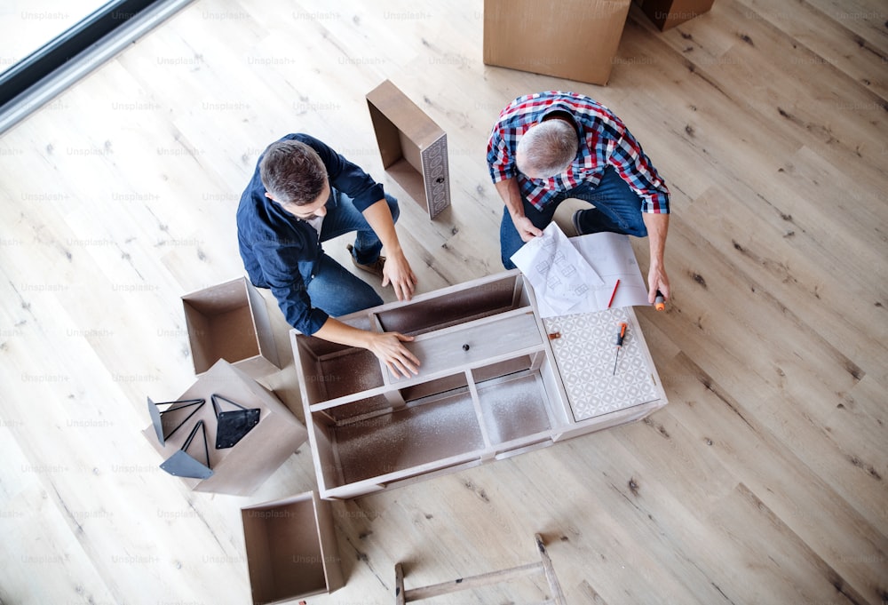 A top view of mature man with his senior father assembling furniture, a new home concept.