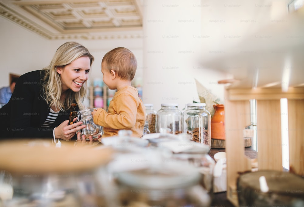 Una giovane donna attraente con un bambino piccolo che compra generi alimentari in un negozio a rifiuti zero.