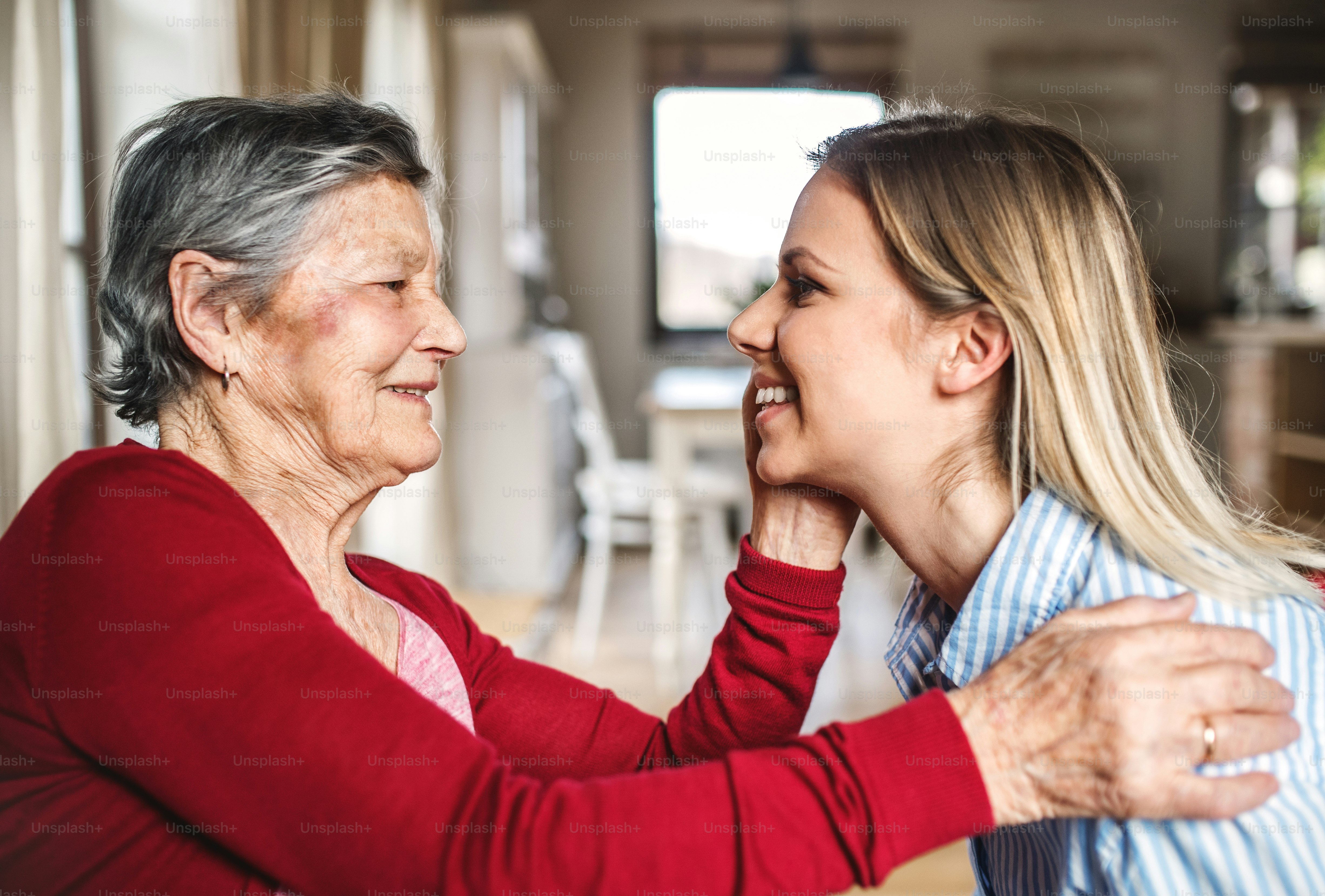 Una nonna anziana che guarda e accarezza una nipote adulta a casa