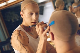 a man with a bald head is getting his makeup done
