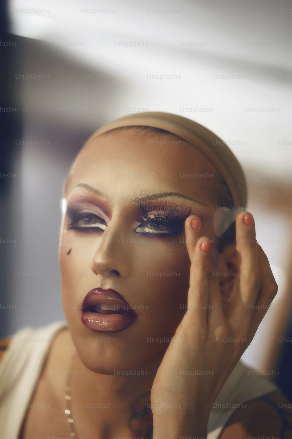 a man with makeup on his face holding his hand up to her face
