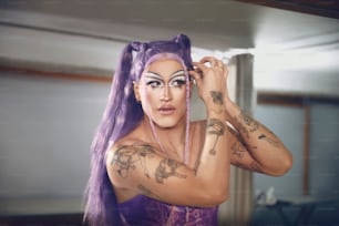 Eine Frau mit lila Haaren und Tätowierungen im Gesicht