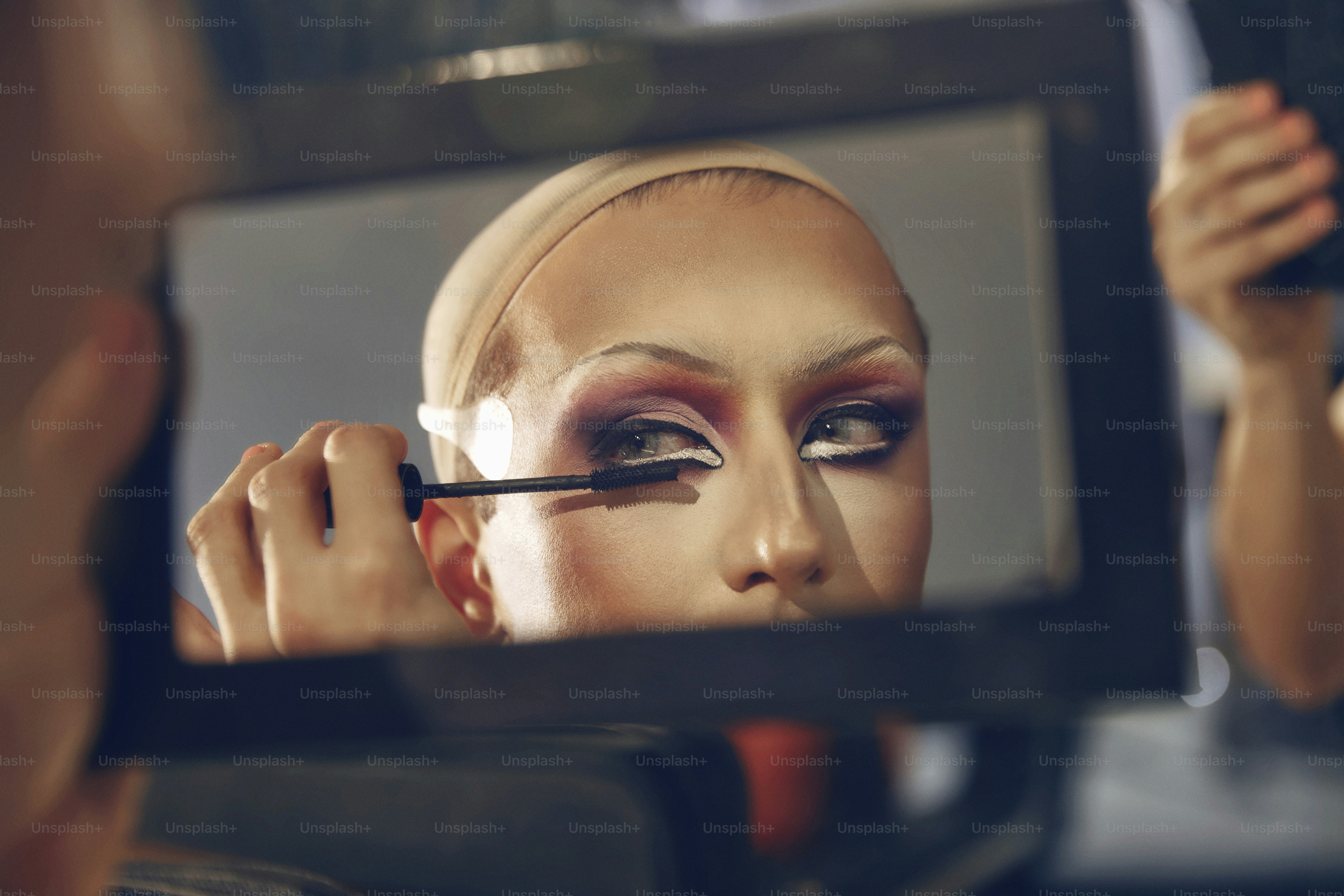 a woman is doing makeup in front of a mirror