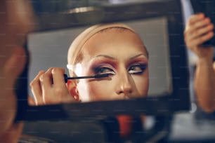 a woman is doing makeup in front of a mirror