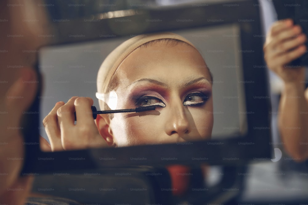 Una mujer se maquilla frente a un espejo