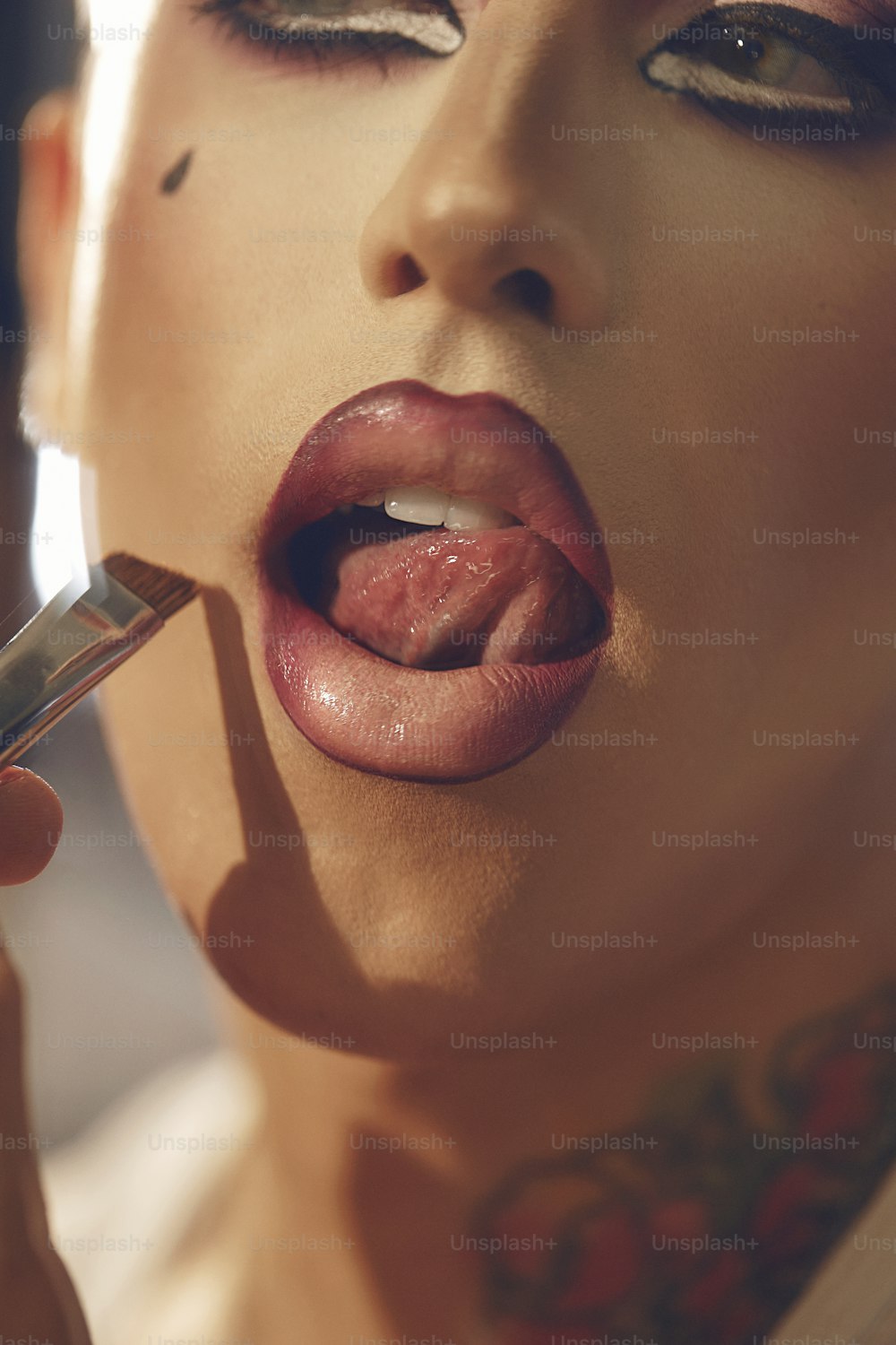 a woman putting lipstick on her lips with a brush