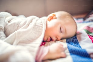 A cute toddler girl sleeping on a bed at home.