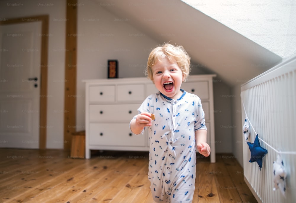 A happy toddler boy in the bedroom at home, having fun.