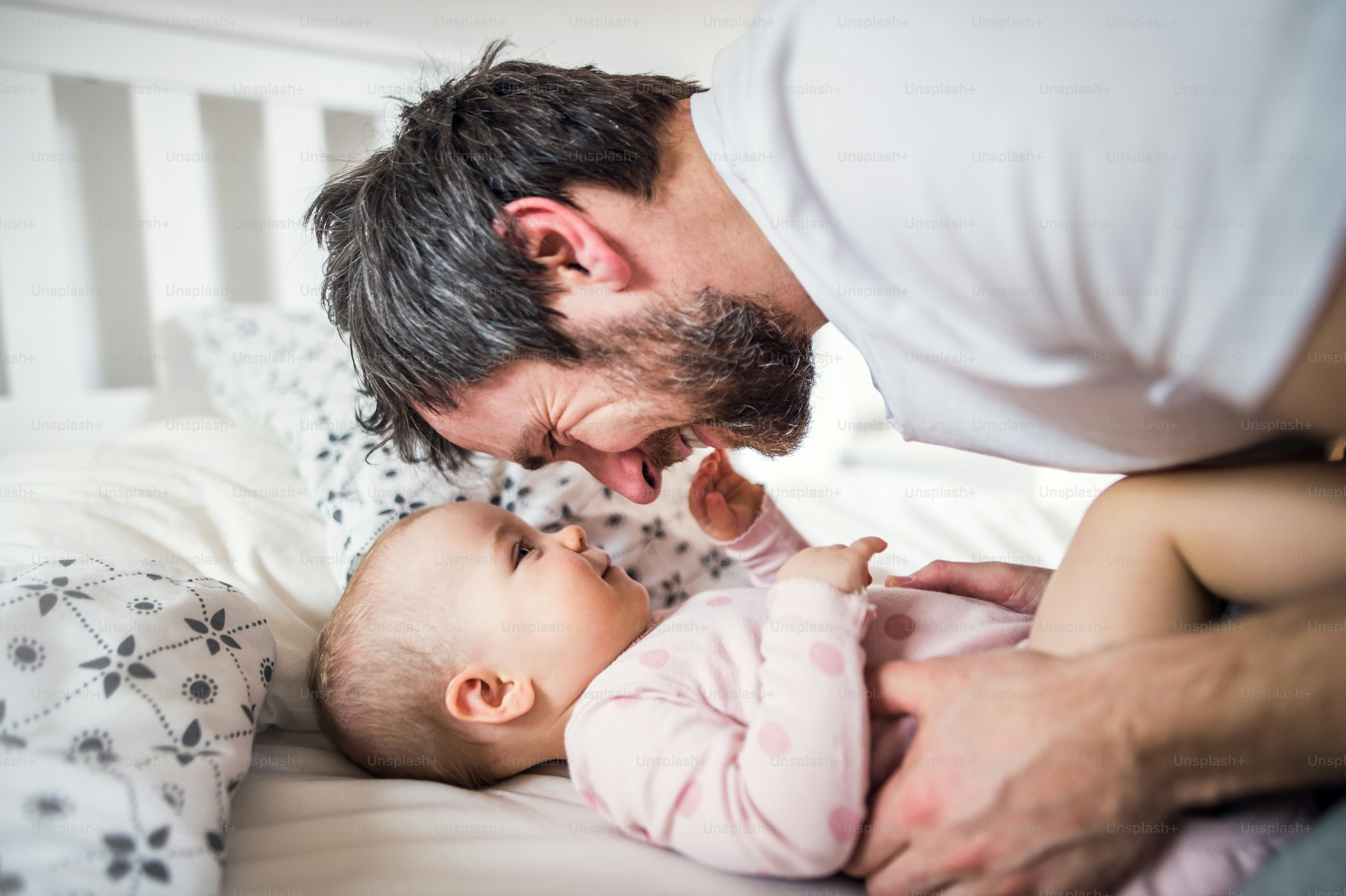 就寝時に自宅でベッドに幼児の女の子を持つ父親。育児休暇。