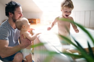 Father washing two toddlers in the bath in the bathroom at home. Paternity leave.