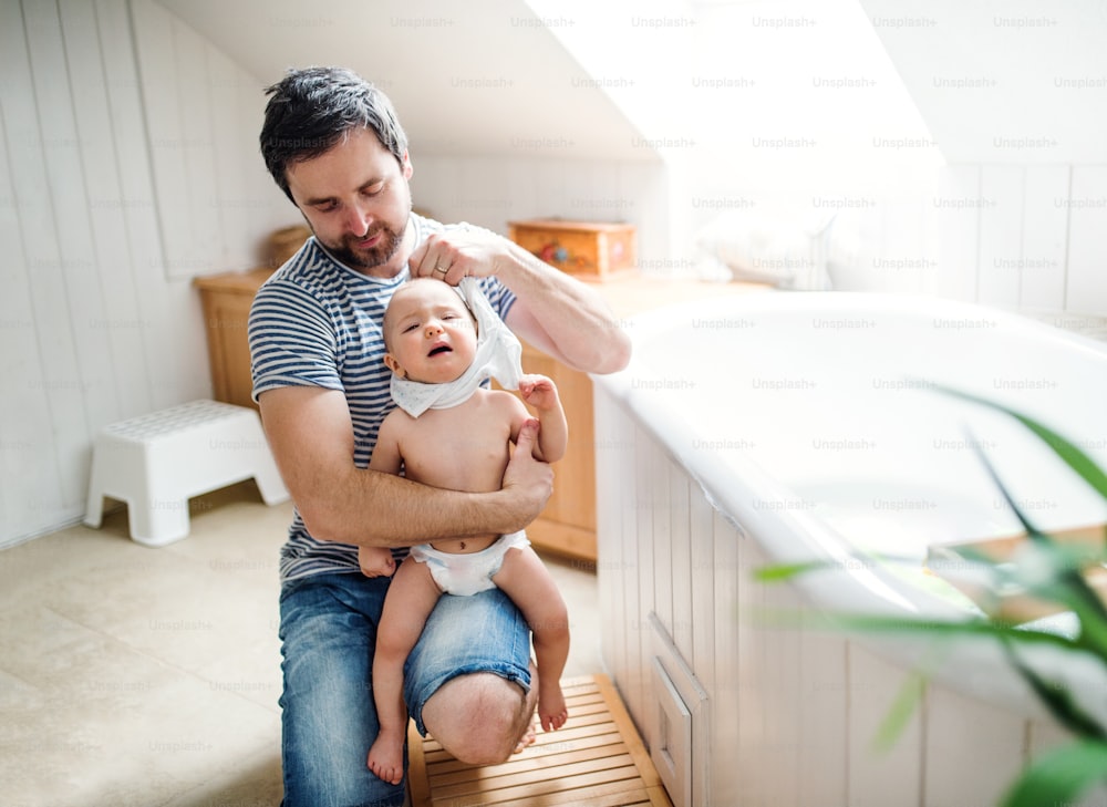 Padre con un bambino piccolo a casa, preparandosi per un bagno. Congedo di paternità.