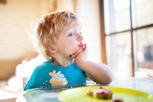 A cute toddler boy eating at home.