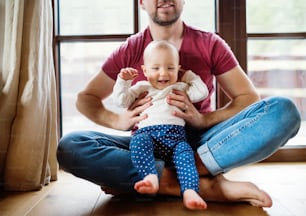 Unrecognizable father with a baby girl at home. Paternity leave.