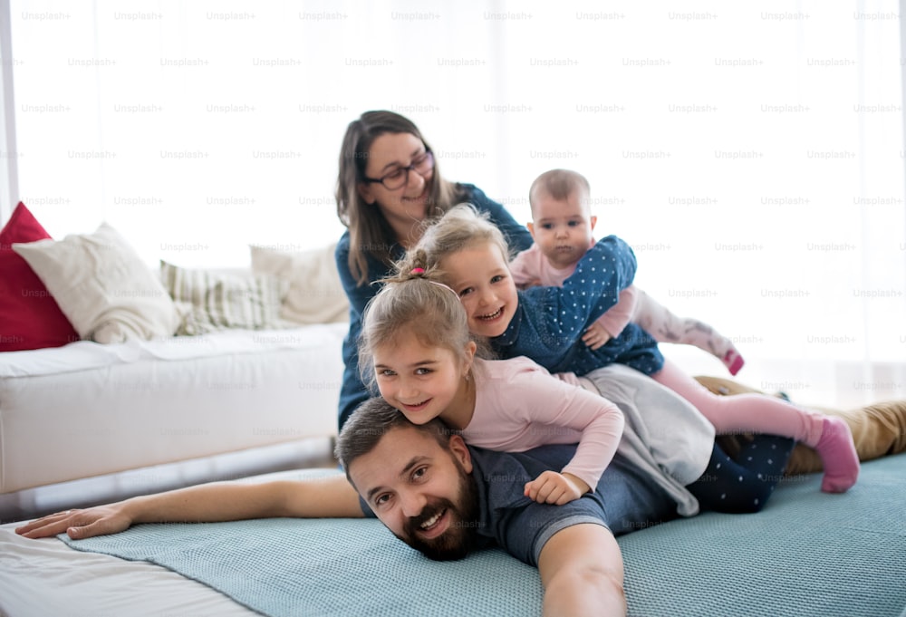 A portrait of young family with small children lying on top of each other on floor indoors, having fun.