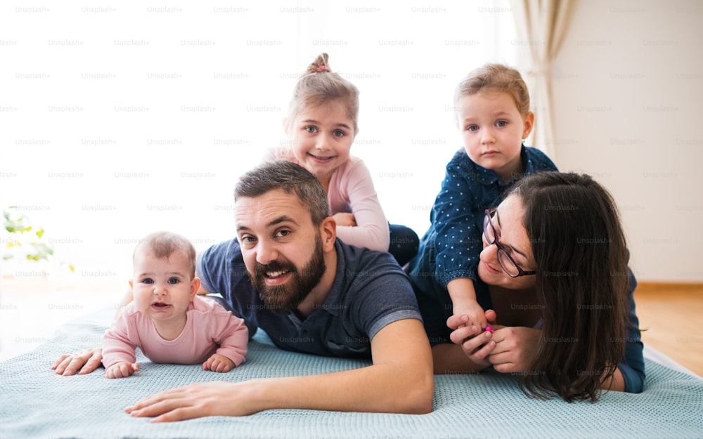 A portrait of young family with small children lying on floor indoors, having fun.