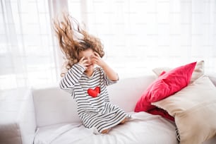 A cute small girl in striped T-shirt at home having fun.