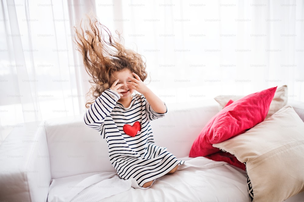 Una linda niña pequeña con camiseta a rayas en casa divirtiéndose.