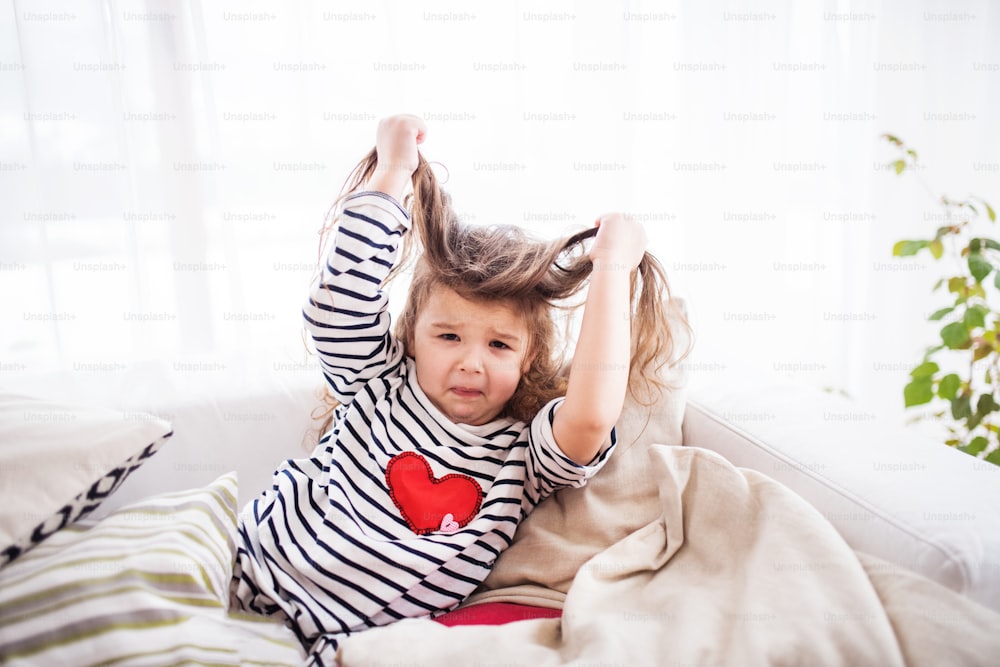 A cute small girl in striped T-shirt at home having fun.