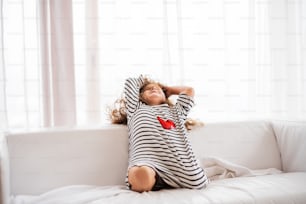 A cute small happy girl in striped T-shirt at home having fun.