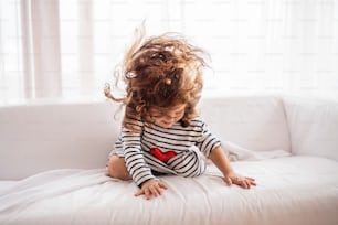 A cute small girl in striped T-shirt at home having fun.