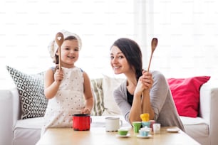 Mãe jovem com uma menina pequena em casa, brincando.