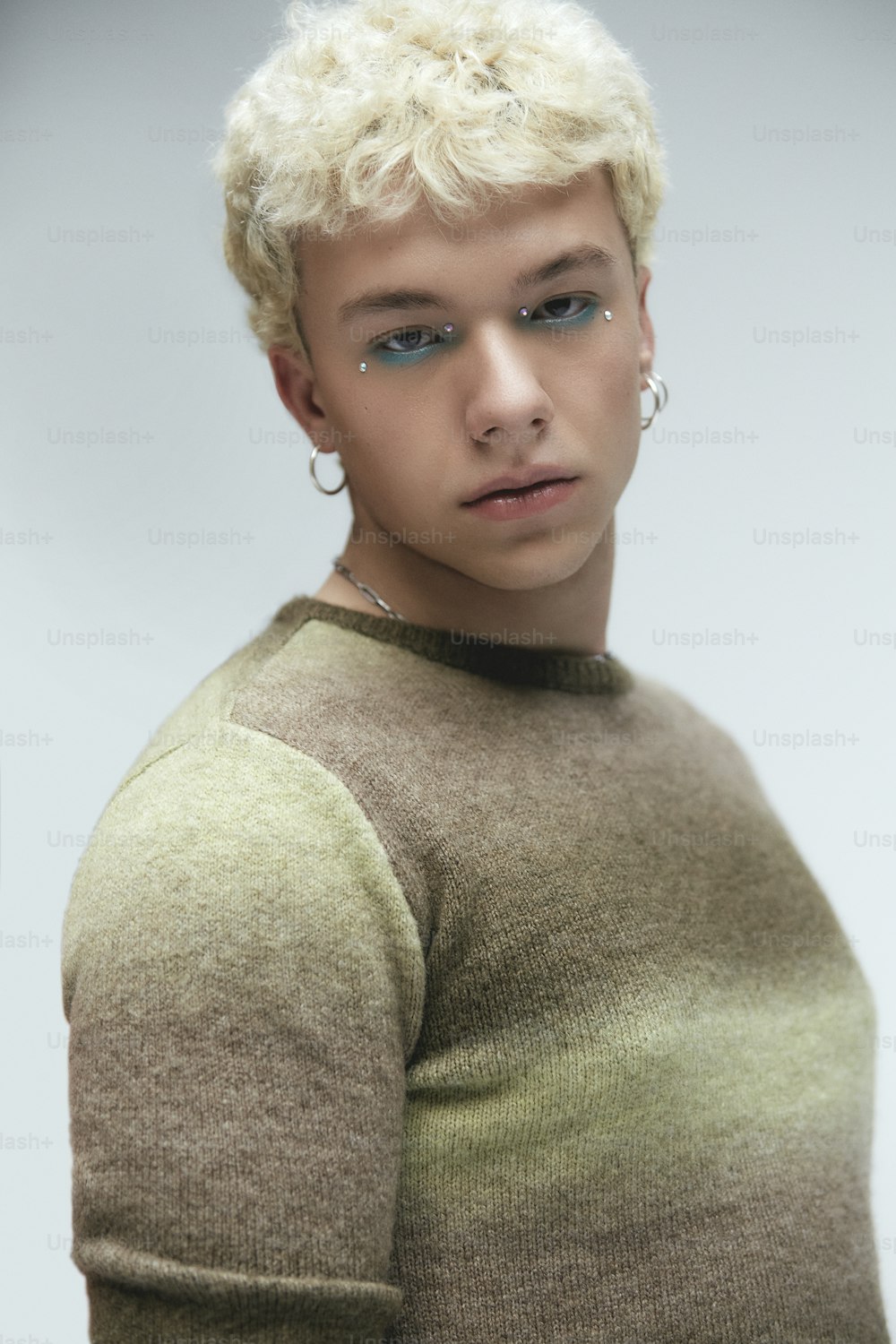 a young man with blonde hair wearing a sweater