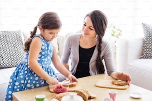 Young mother with a small girl at home, eating.