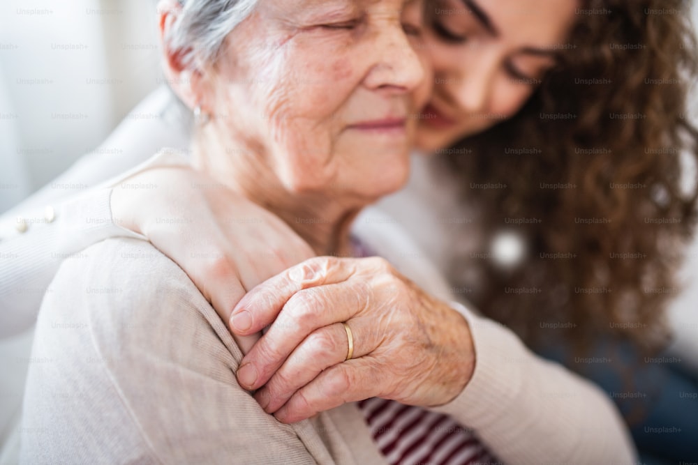 A teenage girl with grandmother at home, hugging. Family and generations concept. Close up.
