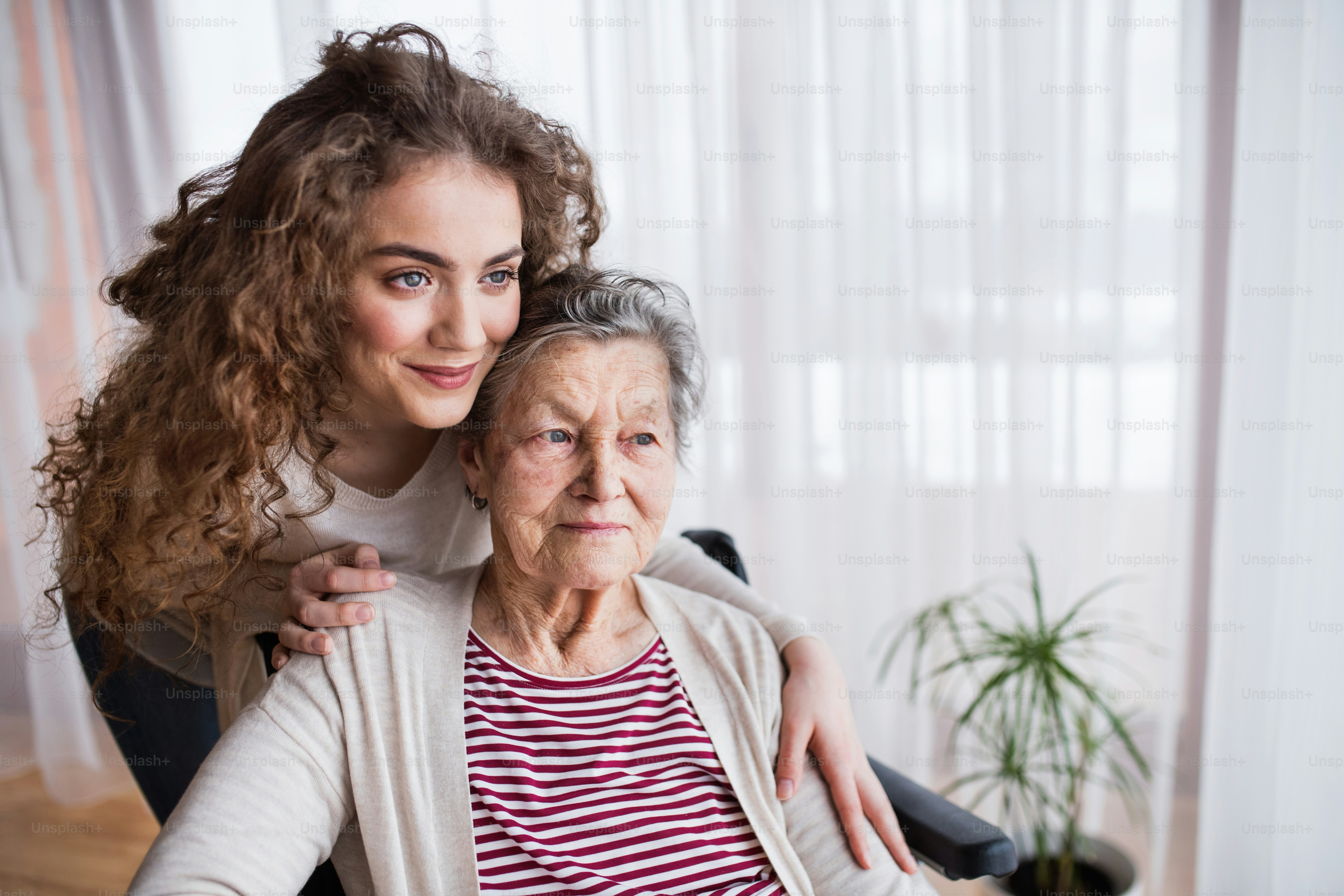 A teenage girl with grandmother at home, hugging. Family and generations concept