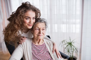 A teenage girl with grandmother at home, hugging. Family and generations concept.