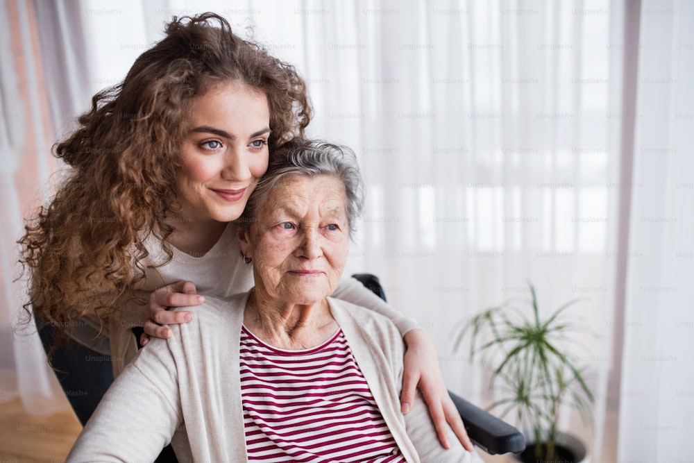 Une adolescente avec grand-mère à la maison, en train de s’étreindre. Concept de famille et de générations.