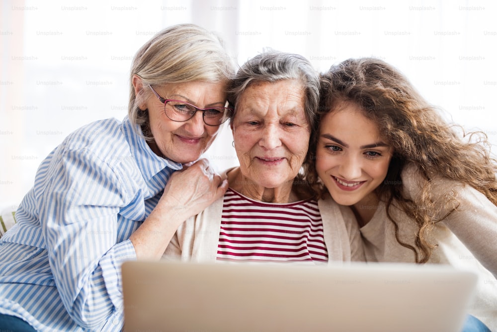 Un'adolescente, sua madre e sua nonna con tablet a casa. Concetto di famiglia e generazioni.