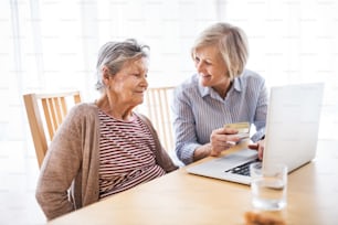 Mujer mayor con su madre con computadora portátil en casa. Concepto de familia y generaciones.