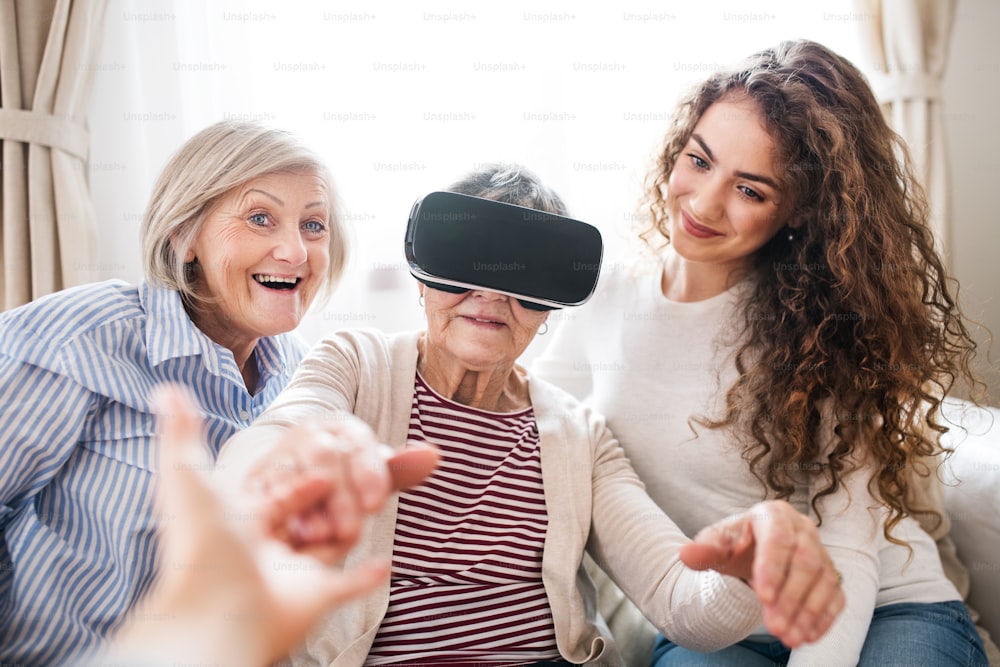 A teenage girl, her mother and grandmother with VR goggles at home. Family and generations concept.
