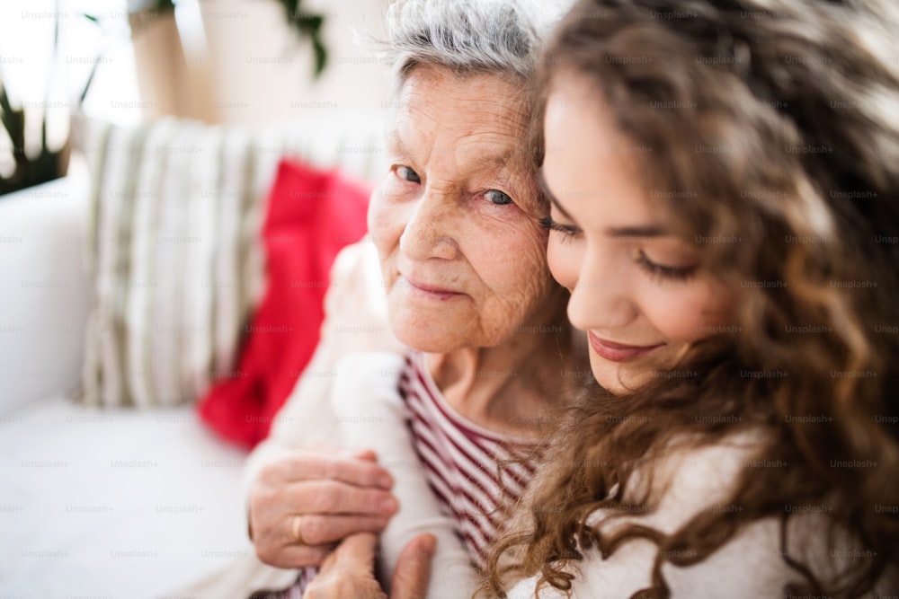 A teenage girl with grandmother at home, hugging. Family and generations concept.