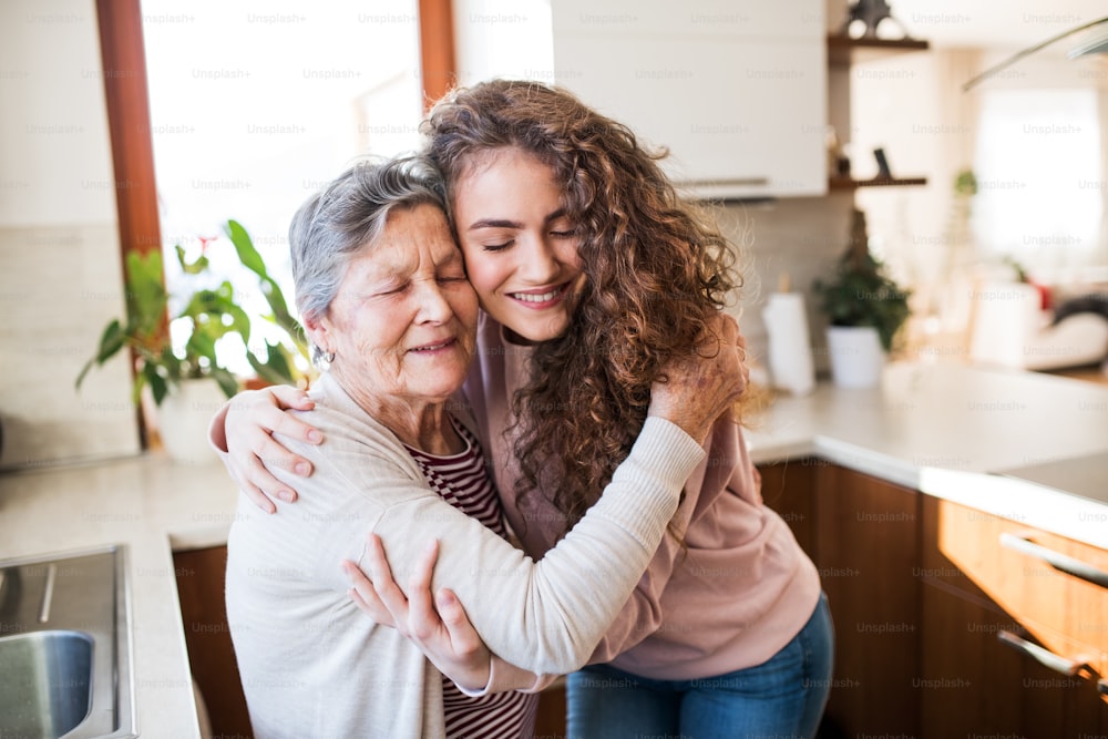 Un'adolescente con la nonna a casa, abbracciata. Concetto di famiglia e generazioni.