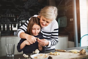 A small girl with her grandmother at home, cooking. Family and generations concept.