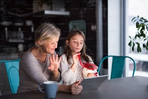 Ein kleines Mädchen und ihre Großmutter mit Tablet zu Hause. Familien- und Generationenkonzept.